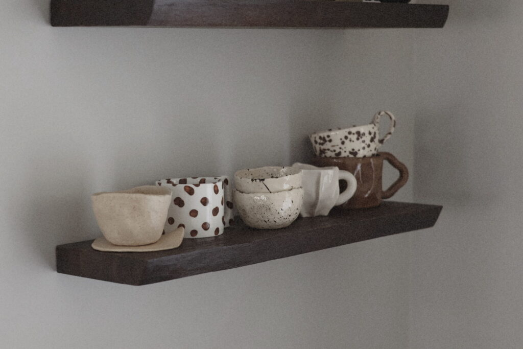 unique beautiful ceramic handmade mugs in brown color pallet on a wooden shelf